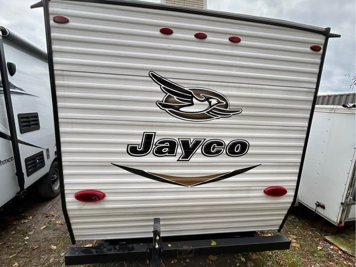 Back of a Jayco travel trailer with Jayco Blue Jay logo on a cloudy day