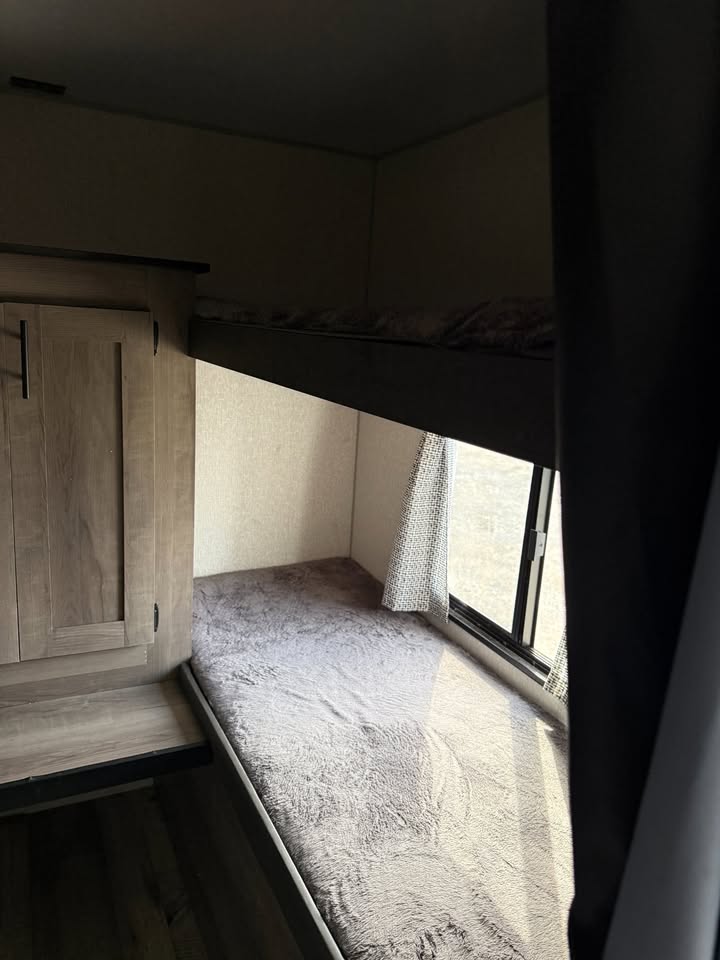 Compact living space with a bunk bed and window in a bunk house room