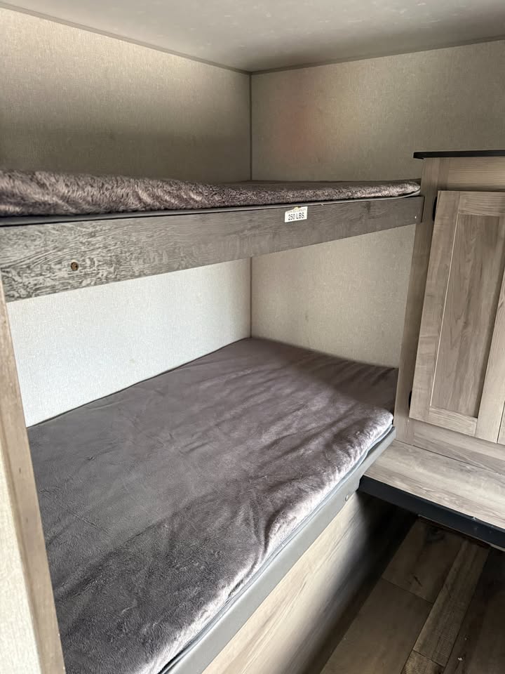 Bunk bed with gray bedding in a compact space, possibly a camper or small room.