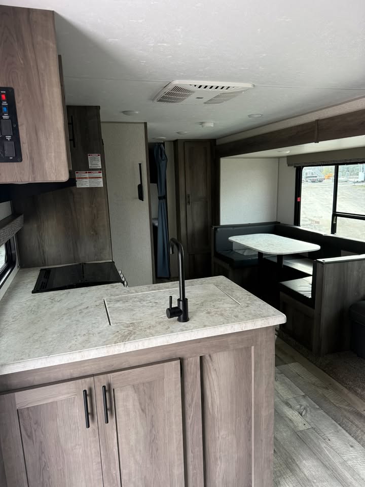 Kitchen area inside a recreational vehicle with countertop, sink, and cabinets.