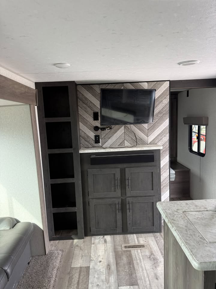 Interior of a modern RV with wooden paneling and entertainment setup.